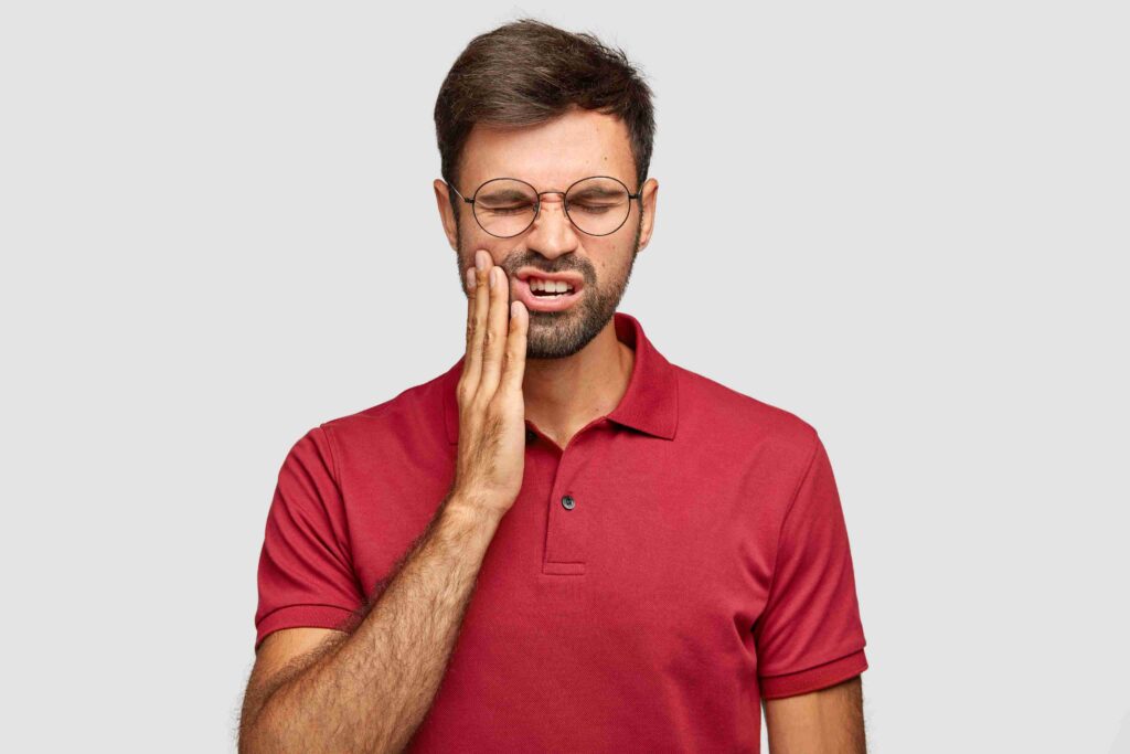 Man holding his cheek due to tooth pain.