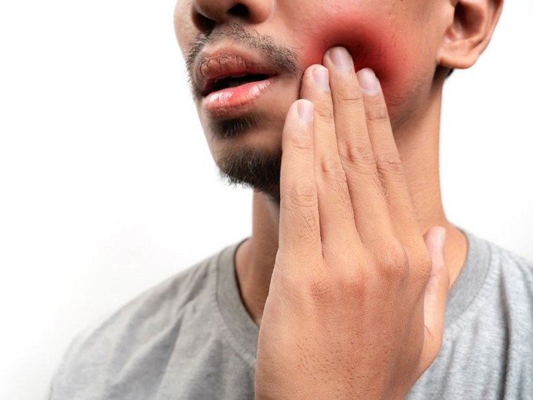 Man holding cheek with tooth pain and swelling