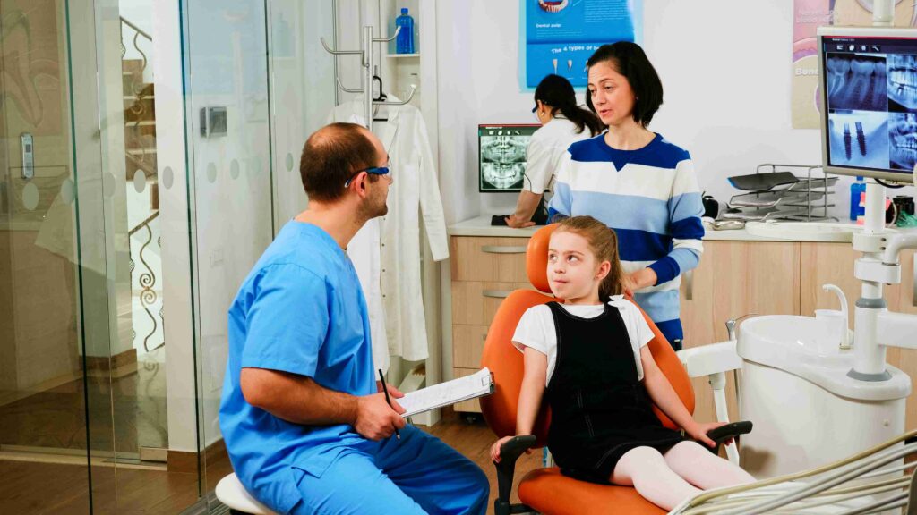 Pediatric dental examination with a child and accompanying mother.