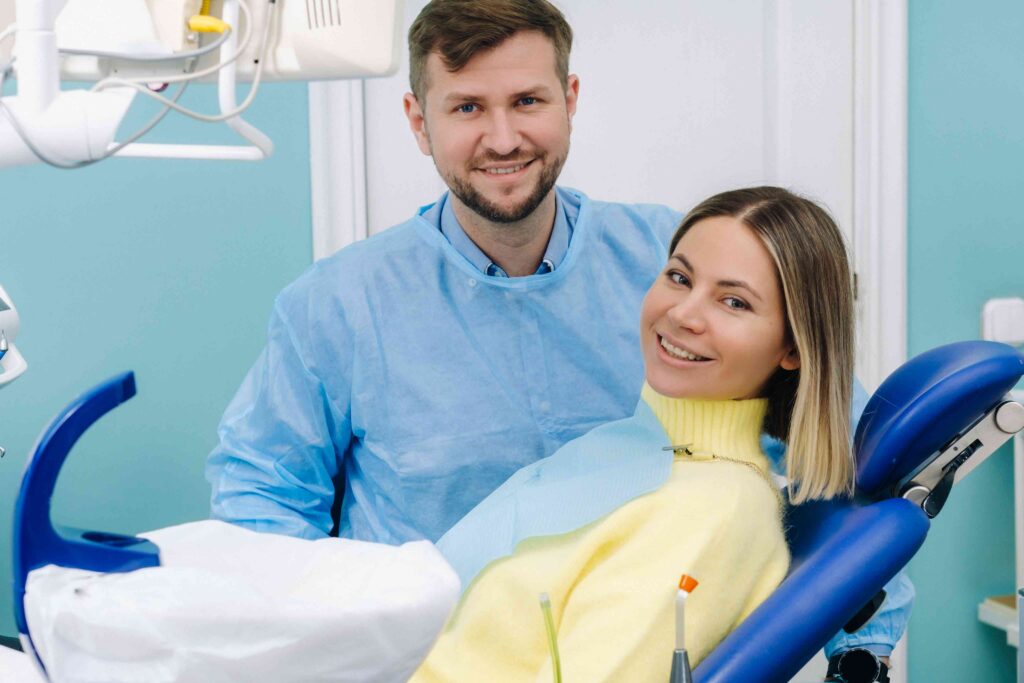 Dentist standing next to a patient seated in a dental chair.